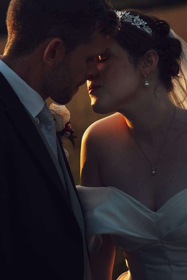 A romantic golden hour images of a newly married couple about to kiss