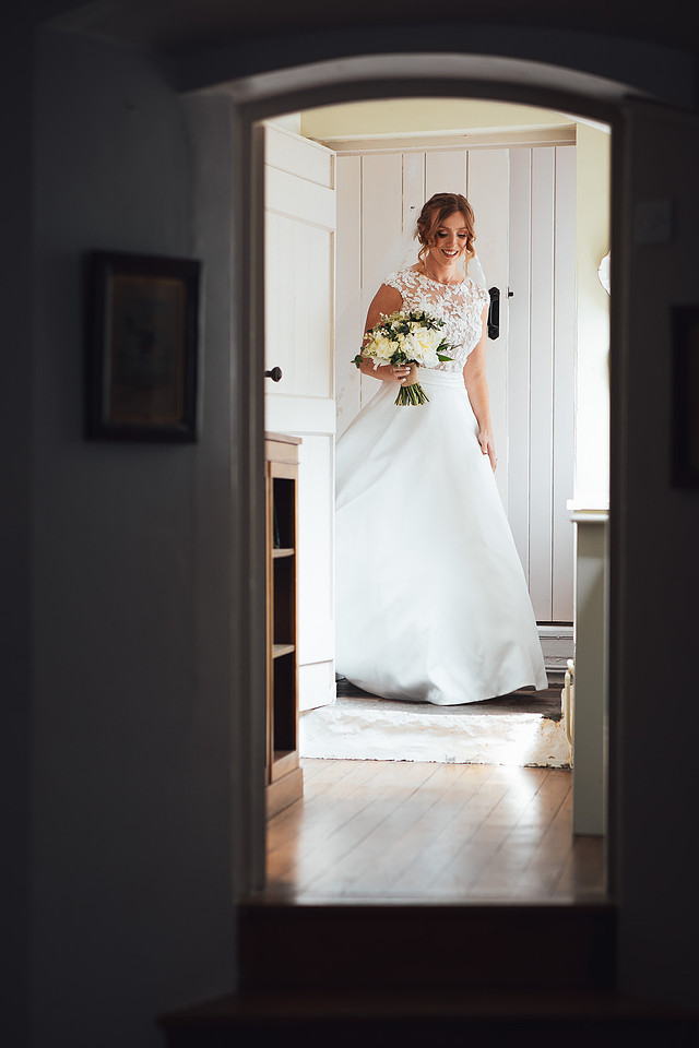 A stunning redhead bride in a designer wedding dress appears from her bridal suite and reveals her outfit for the first time