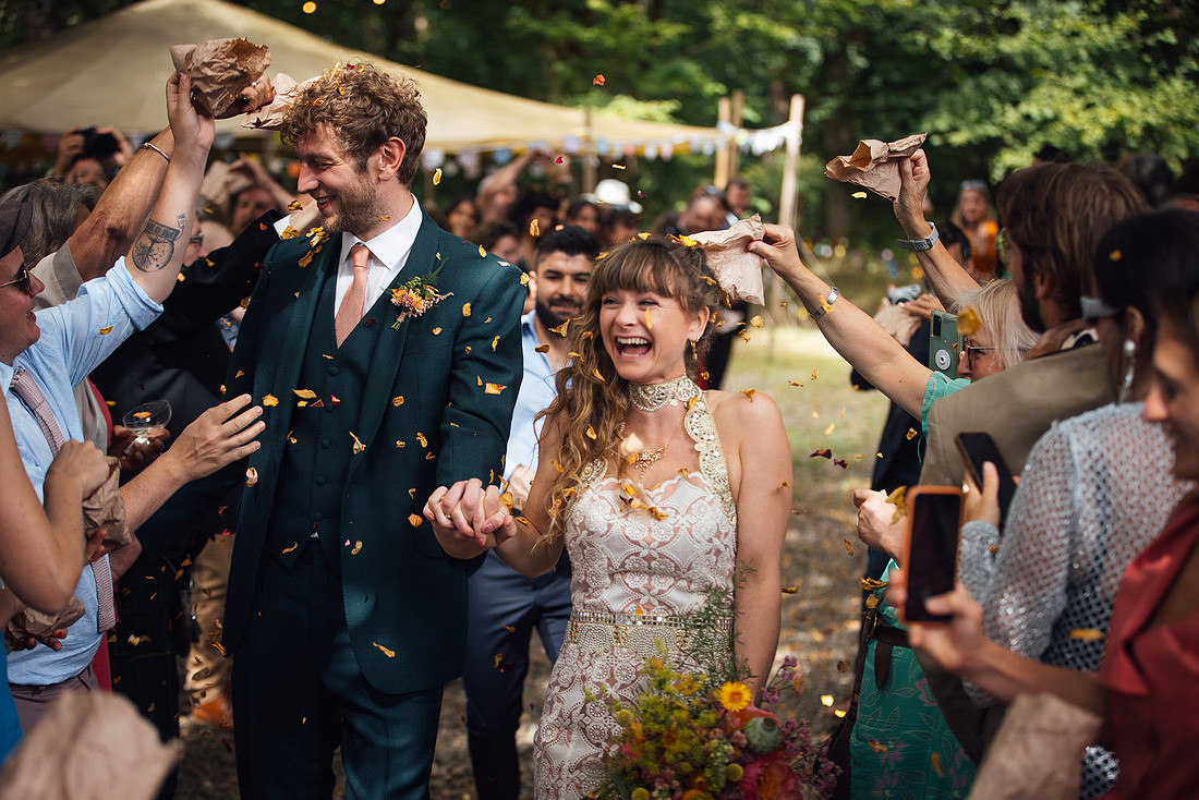 A newly married couple and their guests show absolute joy as they are showered with confetti from their guests at a Pembrokeshire wedding venue