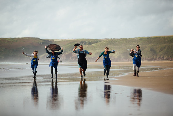 Pembrokeshire beach foods team running accross the beach with pots and pans