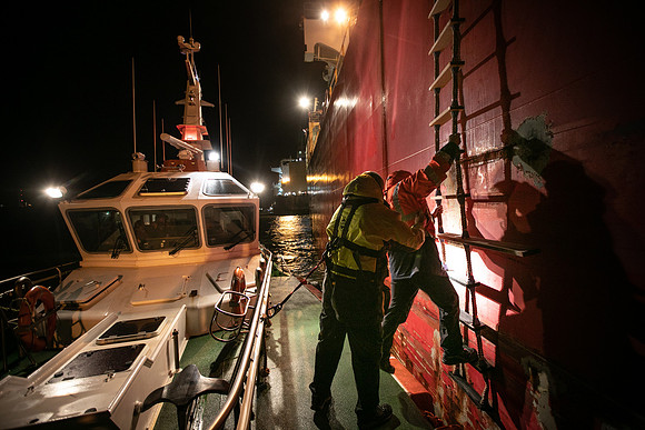 Pilot is supported as they climb the ladder onto an oil tanker