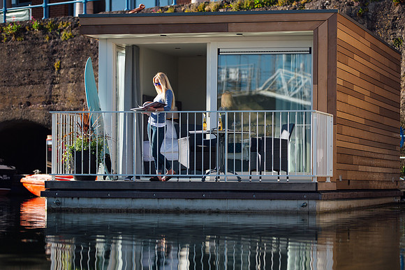 Surfer girl reads a book on the waterside terrace of the floatels in Milford Marina