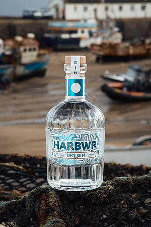 Harbwr Gin bottle with Tenby Harbour and boats in the background