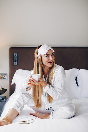 Model sitting on a bed wearing LAID silk eyemask
