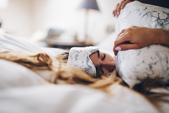 Model lying on a bed wearing LAID silk eyemask