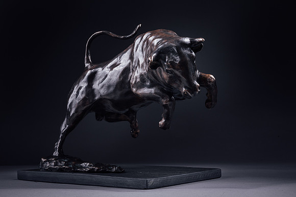 Low key lighting on a galloping bull bronze statue