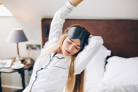 Silk sleeping mask worn by model who is stretching