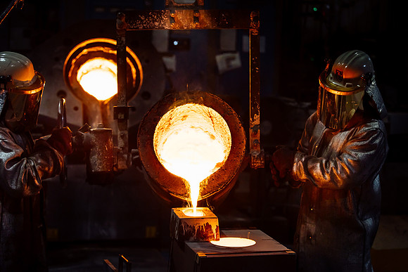 Foundry workers pouring molten metal